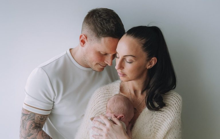 A couple gently embraces their newborn, showcasing love and tenderness.