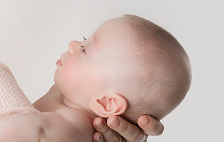 A close-up of a baby's head being gently cradled in a hand.