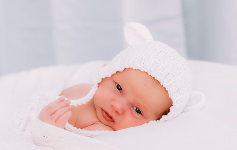 A newborn baby sleeping peacefully in a person's arms.