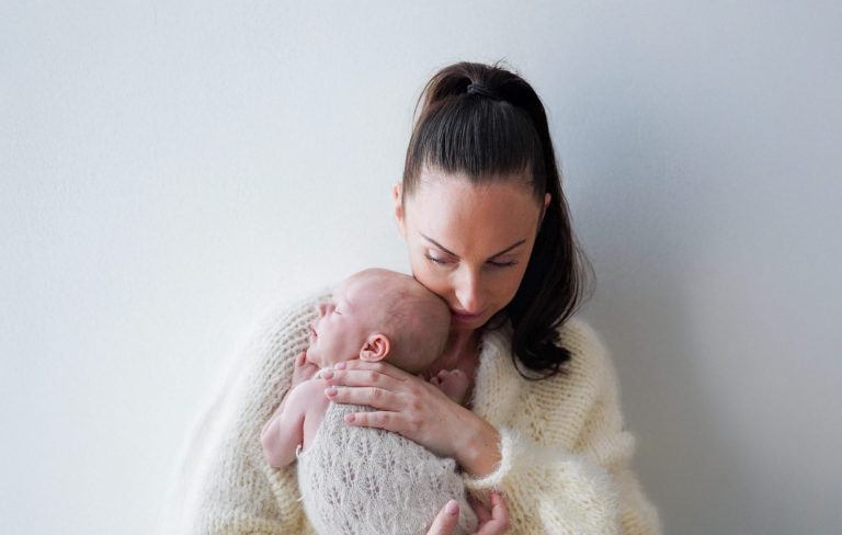 A woman gently holds a baby, both appearing calm and nurturing.